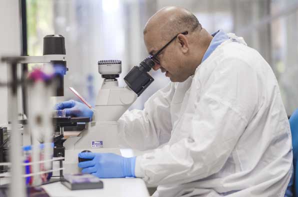 Man in lab coat looking in a microscope