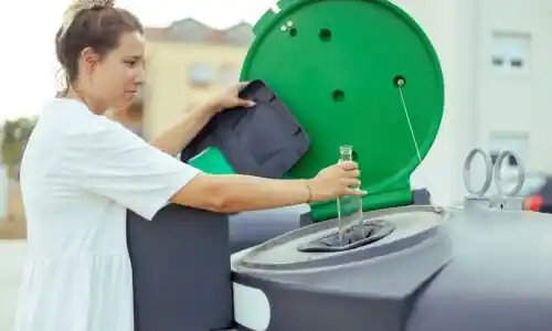 Lady placing glass bottle into recycling bin