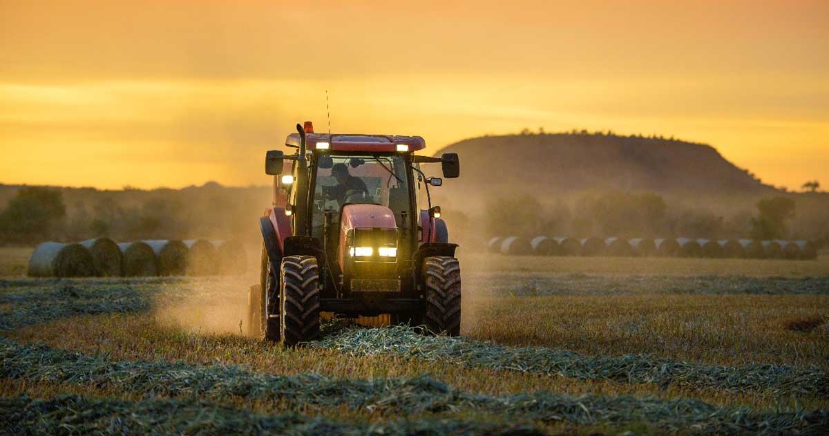 Tractor working in a field at sunset